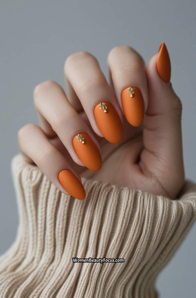 2. Matte Orange Nails with Gold Accents