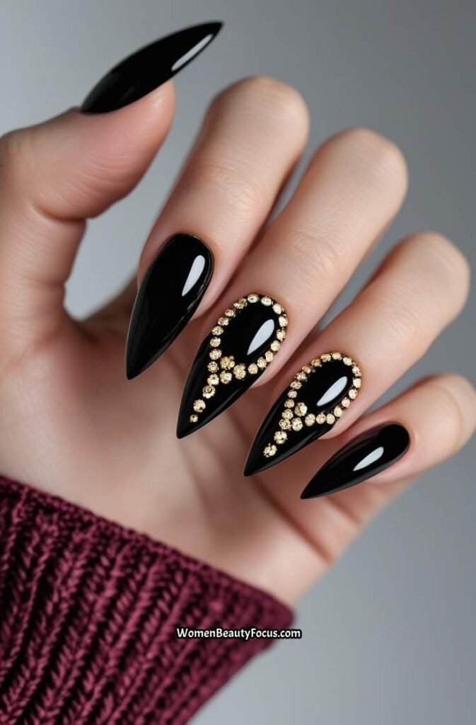 11. Black Stiletto Nails with Gold Rhinestones