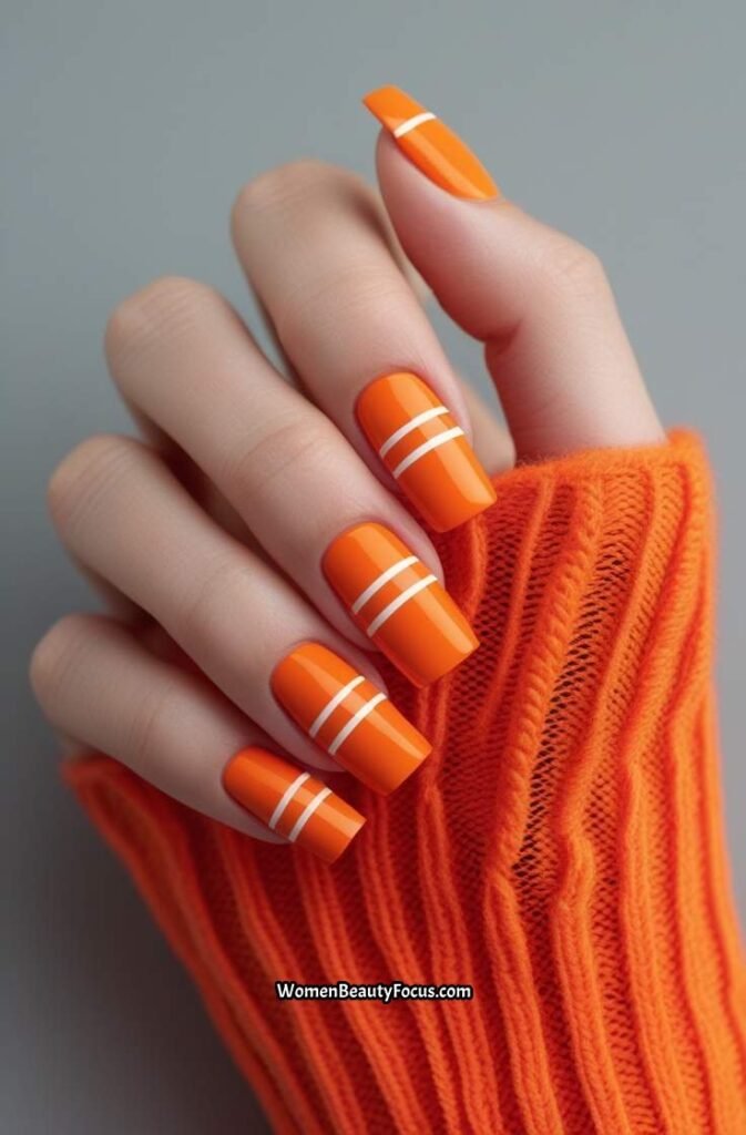 11. Bold Orange Nails with White Stripes